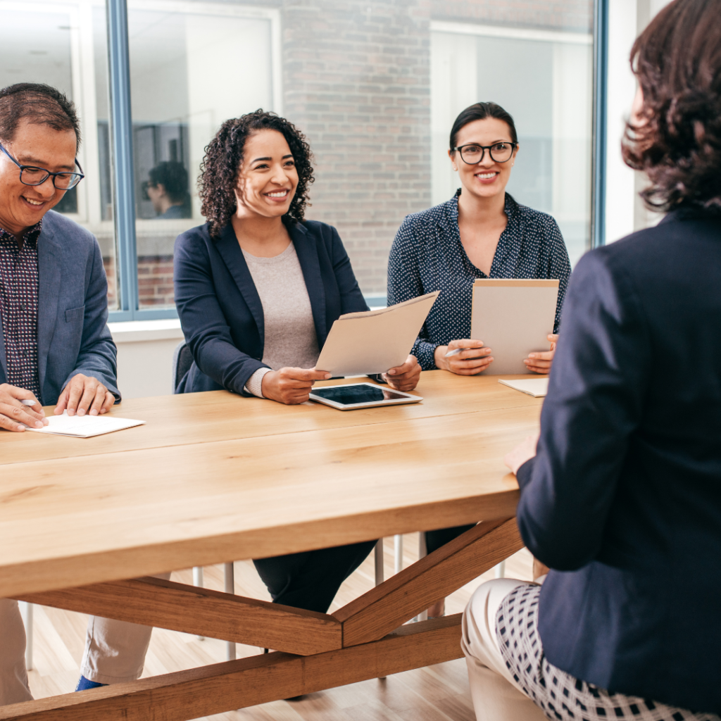Three people interviewing a white women for a job hunting tips